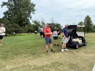 Group of golfers gathered with carts on the course