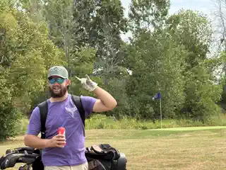 Golfer in a purple memorial shirt beside a golf bag