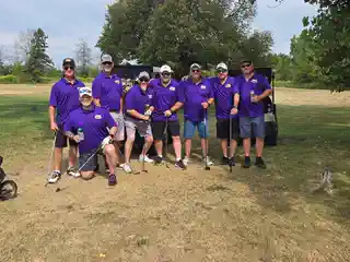 Large golf team posing together at the tournament